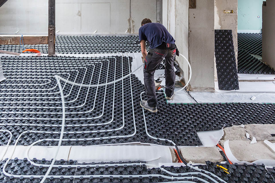 Pipe fitter mounting underfloor radiant heating system